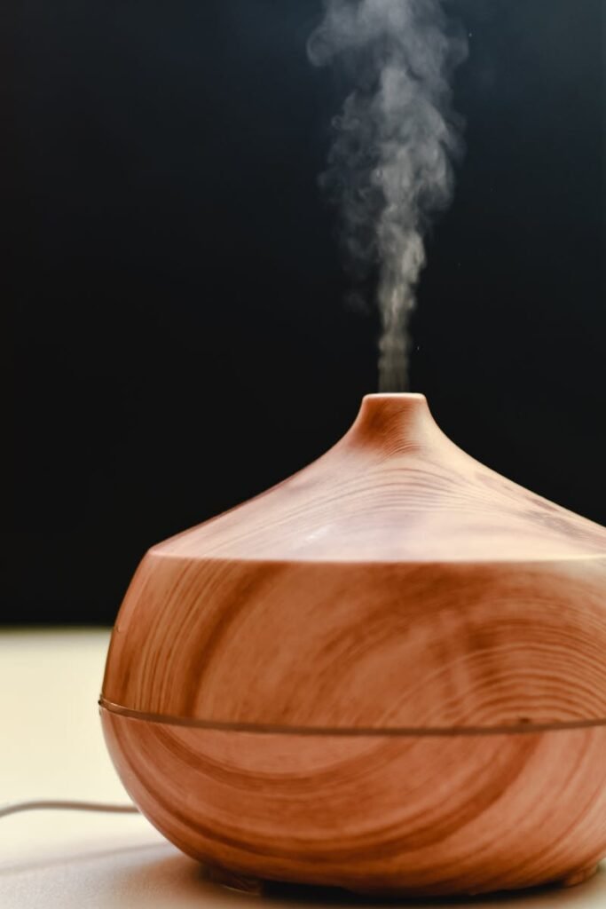 A wooden diffuser releasing calming steam against a black background, ideal for relaxation and aromatherapy stock images.