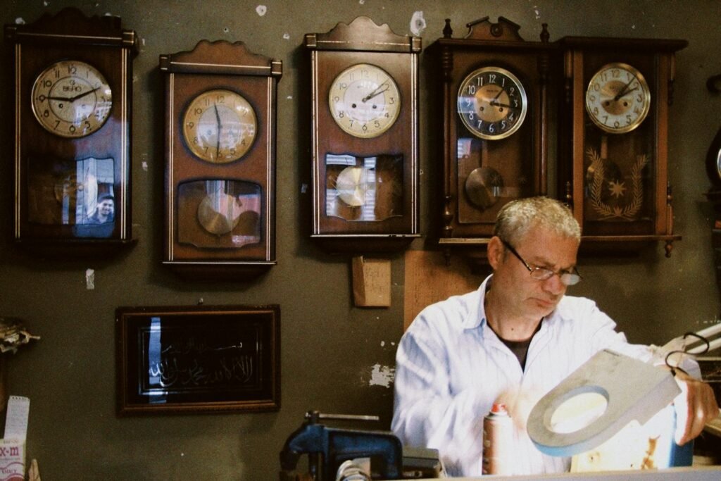 A meticulous watchmaker working intently under magnifying lamp in a vintage clock workshop.