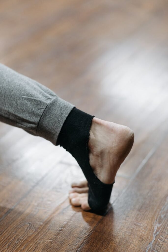 Close-up of a foot stretching on a wooden floor, showcasing flexibility and balance during a workout.