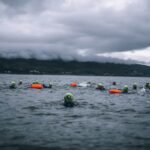 Best Swim Goggles for Open Water - Open water swimmer sighting in lake at sunrise