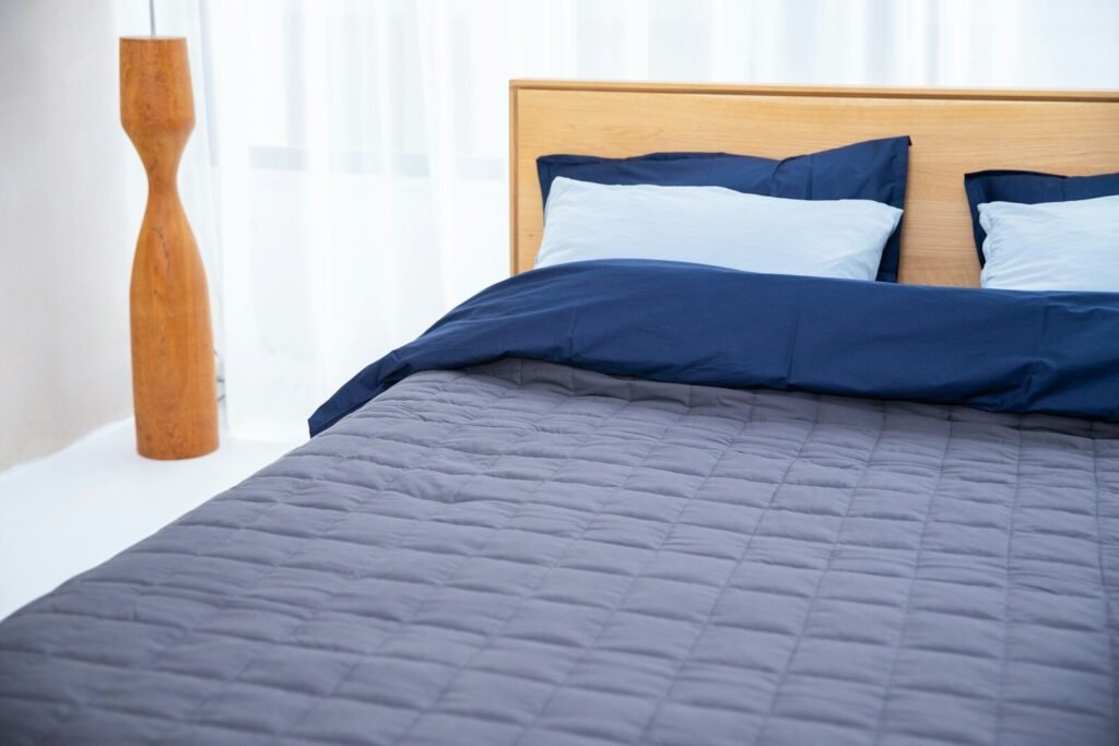 A bed with a blue weighted blanket ready for a deep comfortable sleep 
