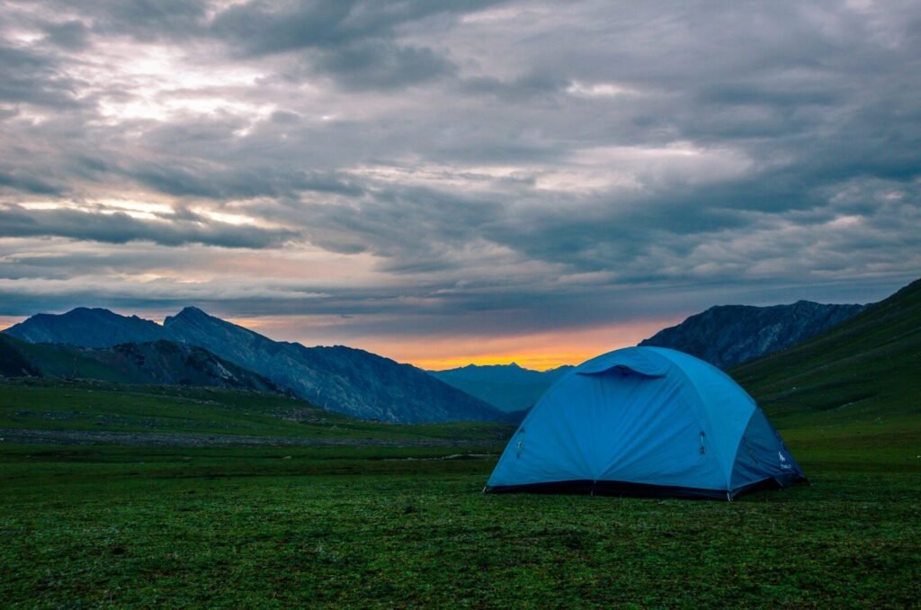 Small backpacking tent pitched on a rocky mountain campsite at dusk