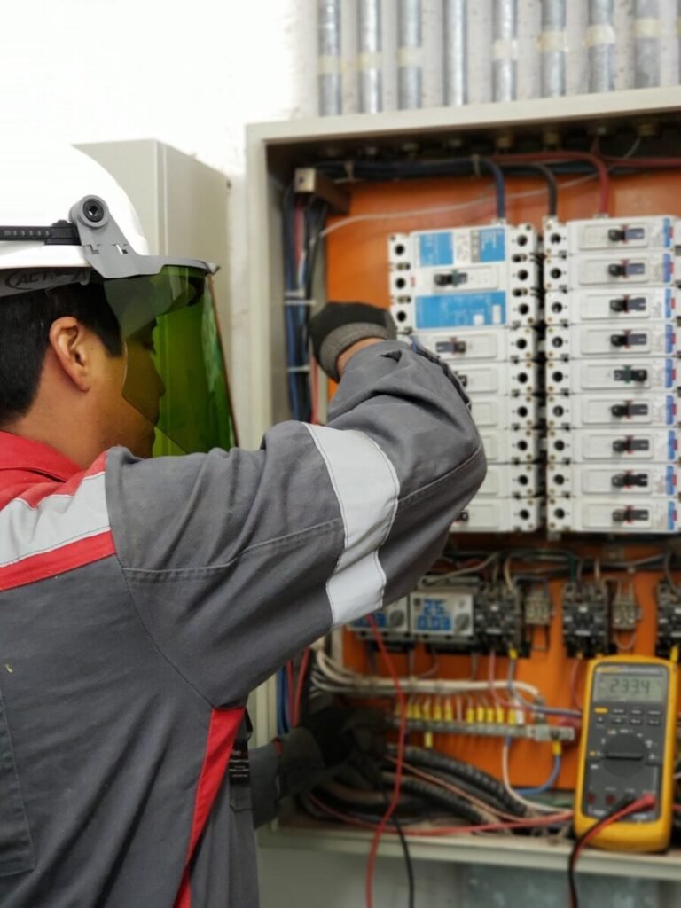 Digital Clamp Meter vs Digital Multimeter - Electrician testing voltage in an industrial breaker panel with a multimeter
