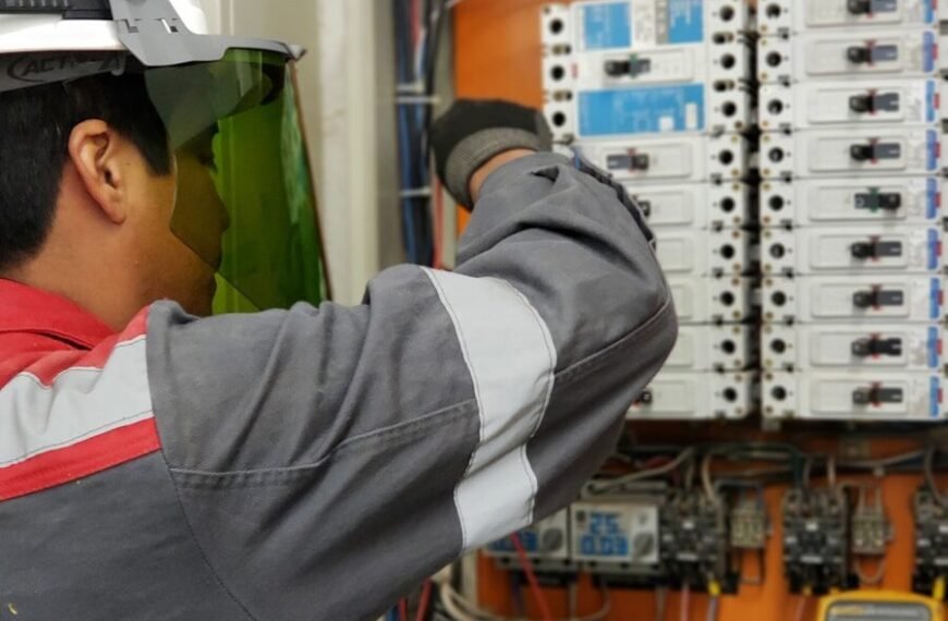 Digital Clamp Meter vs Digital Multimeter - Electrician testing voltage in an industrial breaker panel with a multimeter